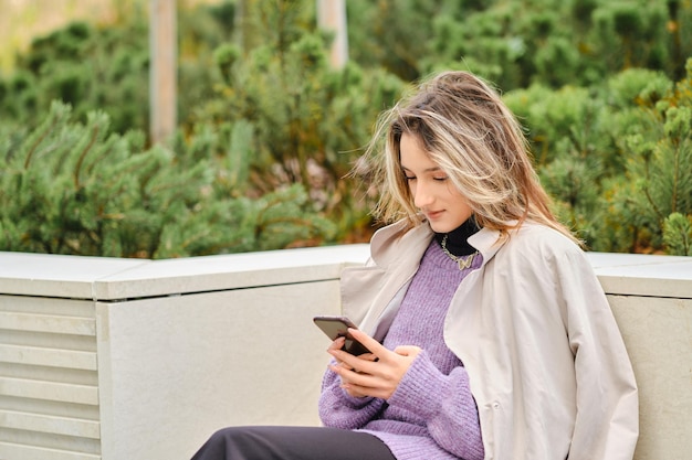 Giovane donna in panchina con lo smartphone