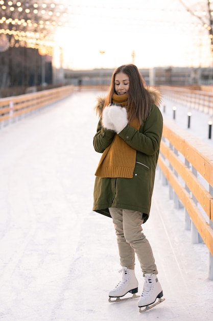 Giovane donna in pattini di figura in piedi sulla pista di pattinaggio all'aperto in inverno day