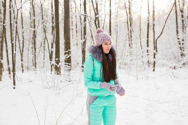 Giovane donna in pelliccia all'aperto nel giardino di neve.