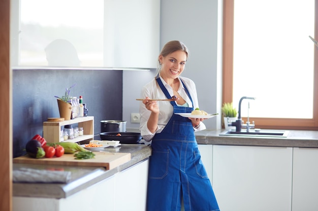 Giovane donna in piedi accanto alla stufa in cucina