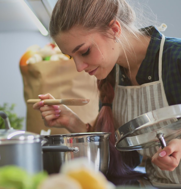 Giovane donna in piedi accanto alla stufa in cucina