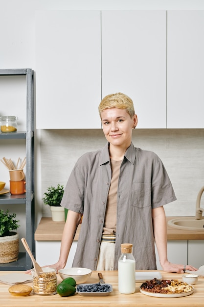 Giovane donna in piedi al tavolo in cucina mentre prepara la colazione