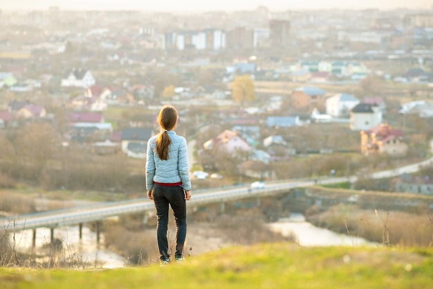 Giovane donna in piedi all'aperto godendo della vista sulla città. Rilassante, libertà e concetto di benessere.