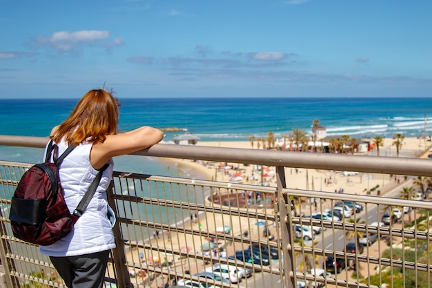 Giovane donna in piedi da solo al balcone di fronte alla spiaggia del mare Immagine per paesaggi, natura, viaggi, persona.