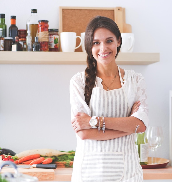 Giovane donna in piedi vicino alla scrivania in cucina Giovane donna