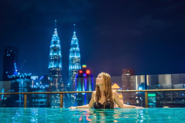Giovane donna in piscina all'aperto con vista sulla città di notte