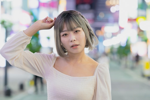 Giovane donna in posa nella città di Tokyo di notte