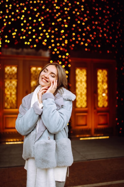 Giovane donna in posa vicino all'albero di Natale durante le vacanze invernali con la stella di Natale.