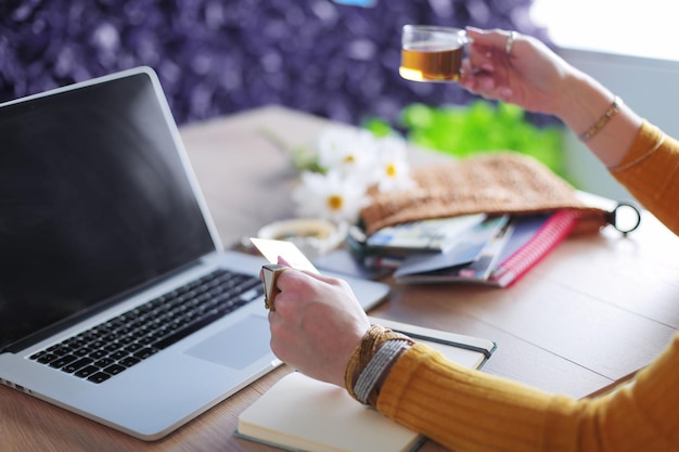 Giovane donna in possesso di carta di credito e utilizzando il computer portatile Concetto di shopping online