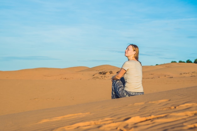 Giovane donna in rad deserto sabbioso al tramonto o all'alba