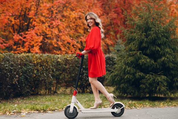 Giovane donna in sella a uno scooter elettrico in autunno city