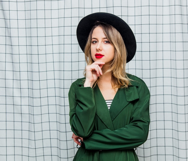 Giovane donna in stile con cappello e mantello verde in stile anni &#39;90