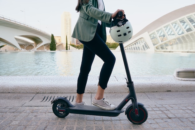 Giovane donna in tuta alla guida di uno scooter elettrico