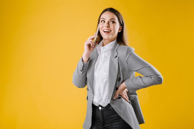 Giovane donna in tuta utilizzando uno smartphone su sfondo giallo