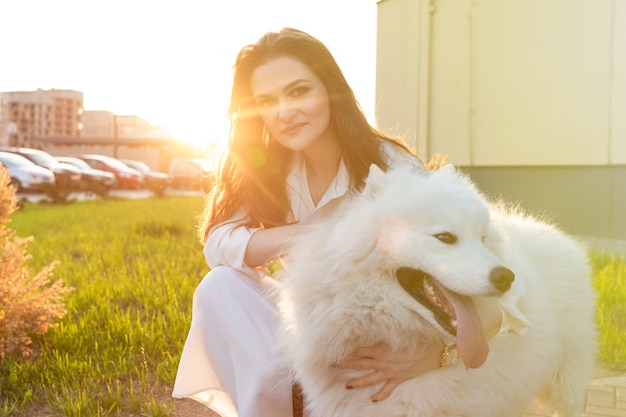 Giovane donna in un abito bianco che abbraccia il suo cane