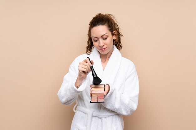 Giovane donna in un accappatoio con palette di trucco