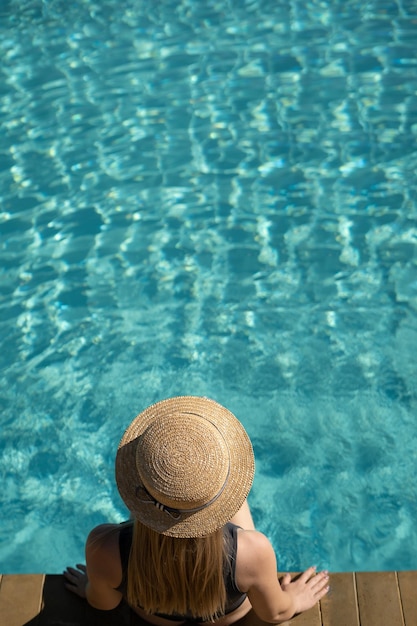 giovane donna in un cappello di paglia sta riposando in piscina Nessuno spazio per la copia del viso