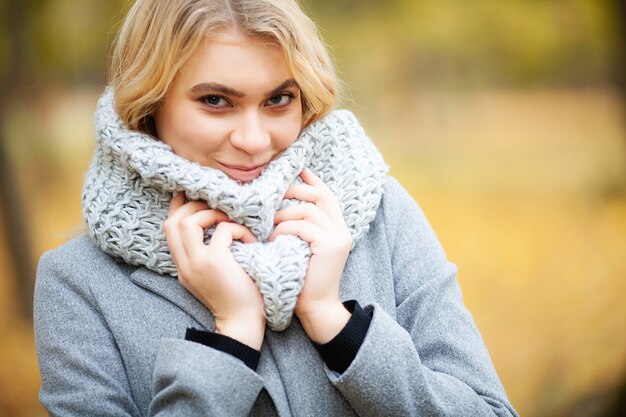 Giovane donna in un cappotto grigio che cammina nel parco di autunno