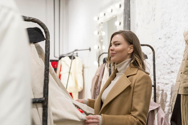 Giovane donna in un negozio di moda Bella bionda in un elegante cappotto beige Moda stile e bellezza