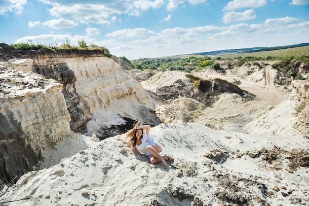 Giovane donna in un panno casual rilassarsi sulle rocce di sabbia, periodo estivo
