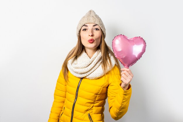 Giovane donna in un piumino giallo e un cappello isolato