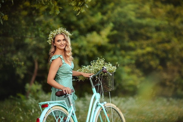 Giovane donna in un vestito con una bici e un mazzo di fiori di campo
