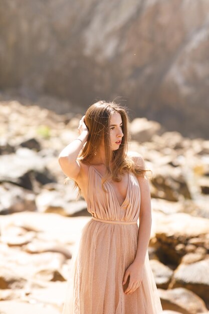 giovane donna in un vestito lungo che cammina sulla spiaggia vicino all'oceano.