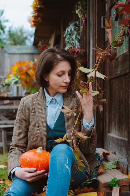 giovane donna in una giacca calda marrone e jeans su fondo rustico.