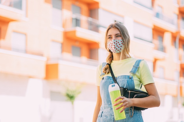 Giovane donna in una maschera di acqua potabile e passeggiate per la città