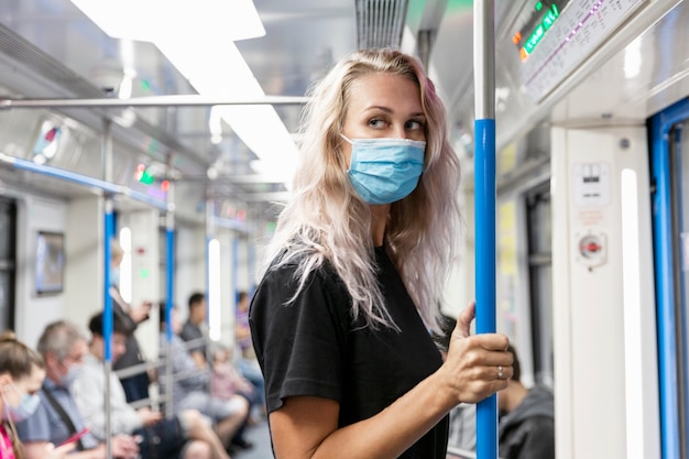 Giovane donna in una mascherina medica in un vagone della metropolitana.