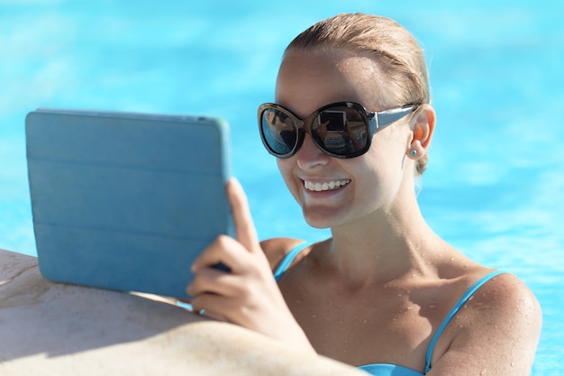 Giovane donna in una piscina utilizzando computer tablet