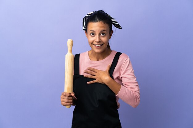 Giovane donna in uniforme da chef sorpresa e scioccata mentre guarda a destra