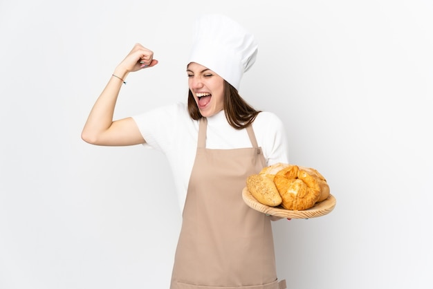 Giovane donna in uniforme del cuoco unico su bianco che celebra una vittoria