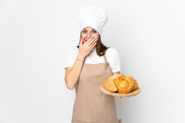 Giovane donna in uniforme del cuoco unico su bianco con espressione facciale di sorpresa