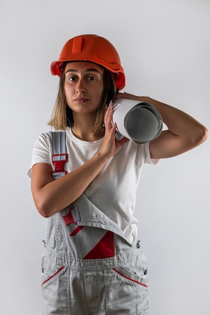 Giovane donna in uniforme di un operaio edile e un casco in testa in posa per un ritratto isolato su uno sfondo bianco Ritratto di una donna architetto costruttore