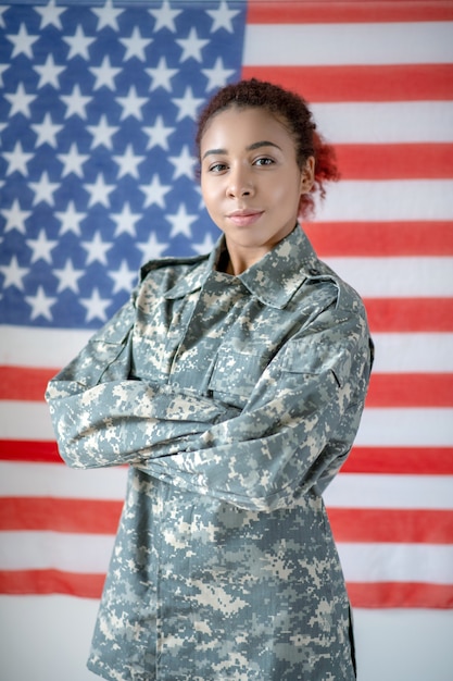 Giovane donna in uniforme militare con la bandiera americana