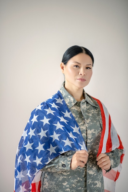 Giovane donna in uniforme militare con la bandiera americana