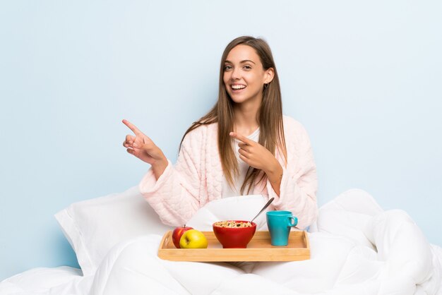 Giovane donna in vestaglia con colazione che punta il dito verso il lato