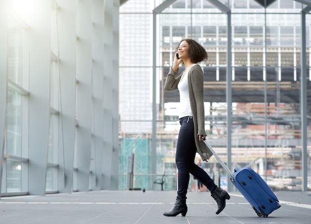 Giovane donna in viaggio con il cellulare e la valigia