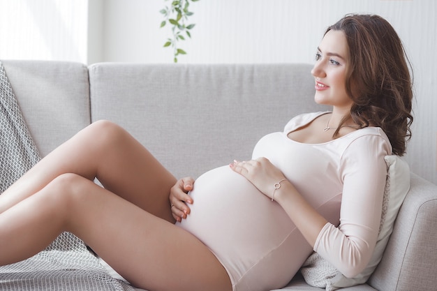 Giovane donna incinta attraente a casa. Chiudere l'immagine della donna in attesa.