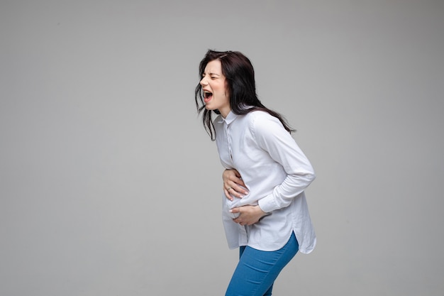 Giovane donna incinta caucasica con i capelli scuri che urla e dà alla luce un bambino