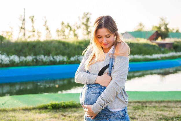 Giovane donna incinta che abbraccia il suo stomaco all'aperto