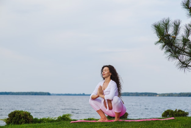 Giovane donna incinta che fa yoga all'aperto