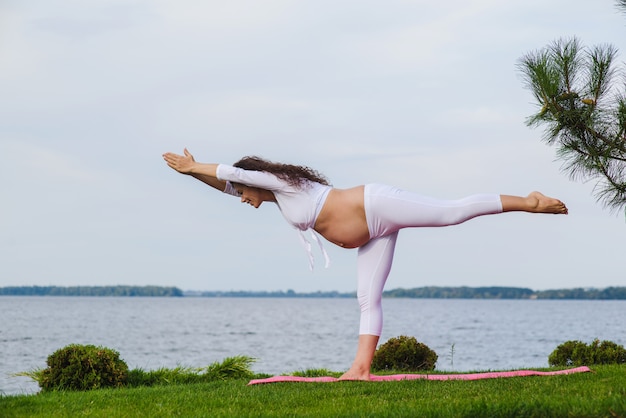 Giovane donna incinta che fa yoga all'aperto