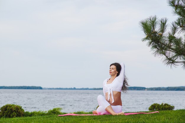 Giovane donna incinta che fa yoga all'aperto