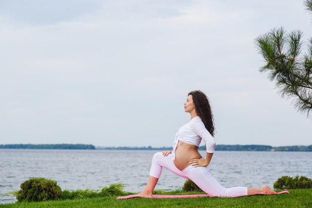 Giovane donna incinta che fa yoga all'aperto