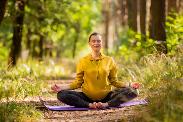 giovane donna incinta che fa yoga in estate nella foresta