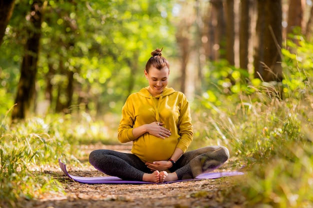 giovane donna incinta che fa yoga in estate nella foresta