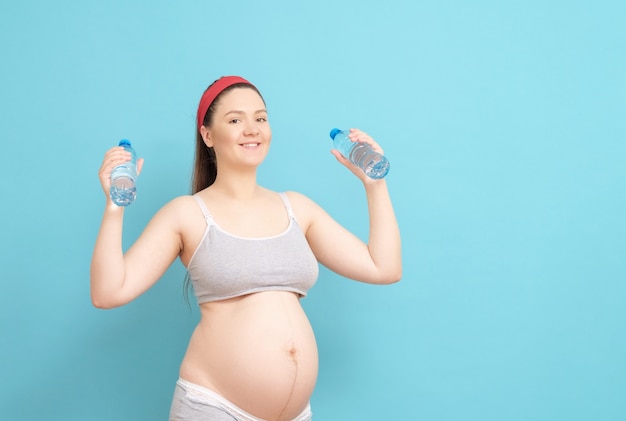 Giovane donna incinta con bottiglie d'acqua