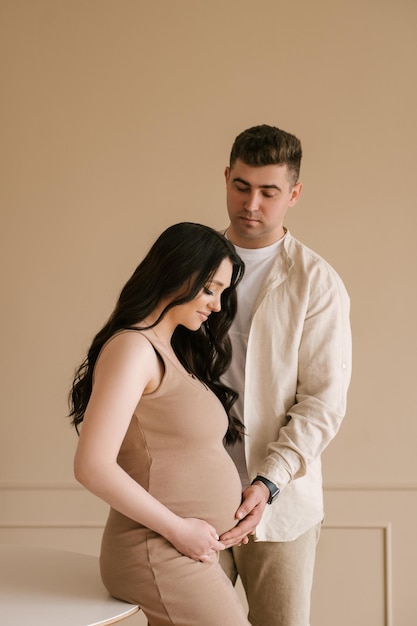 Giovane donna incinta con il marito a casa famiglia felice e concetto di gravidanza